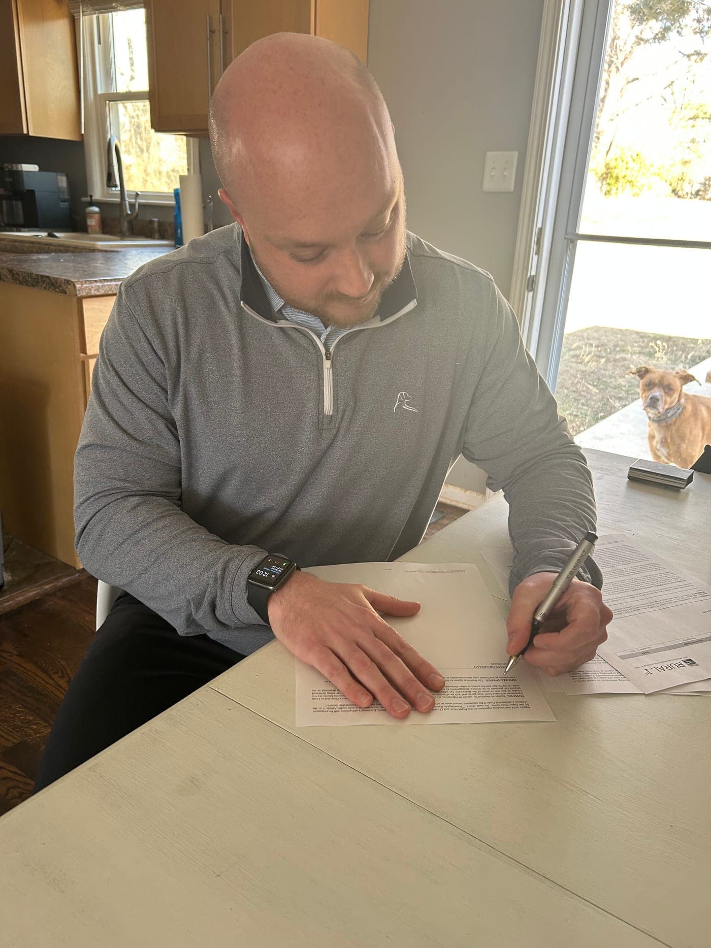 Jeremy signing closing documents on the 11.5 acres, with his dog Milly in the background